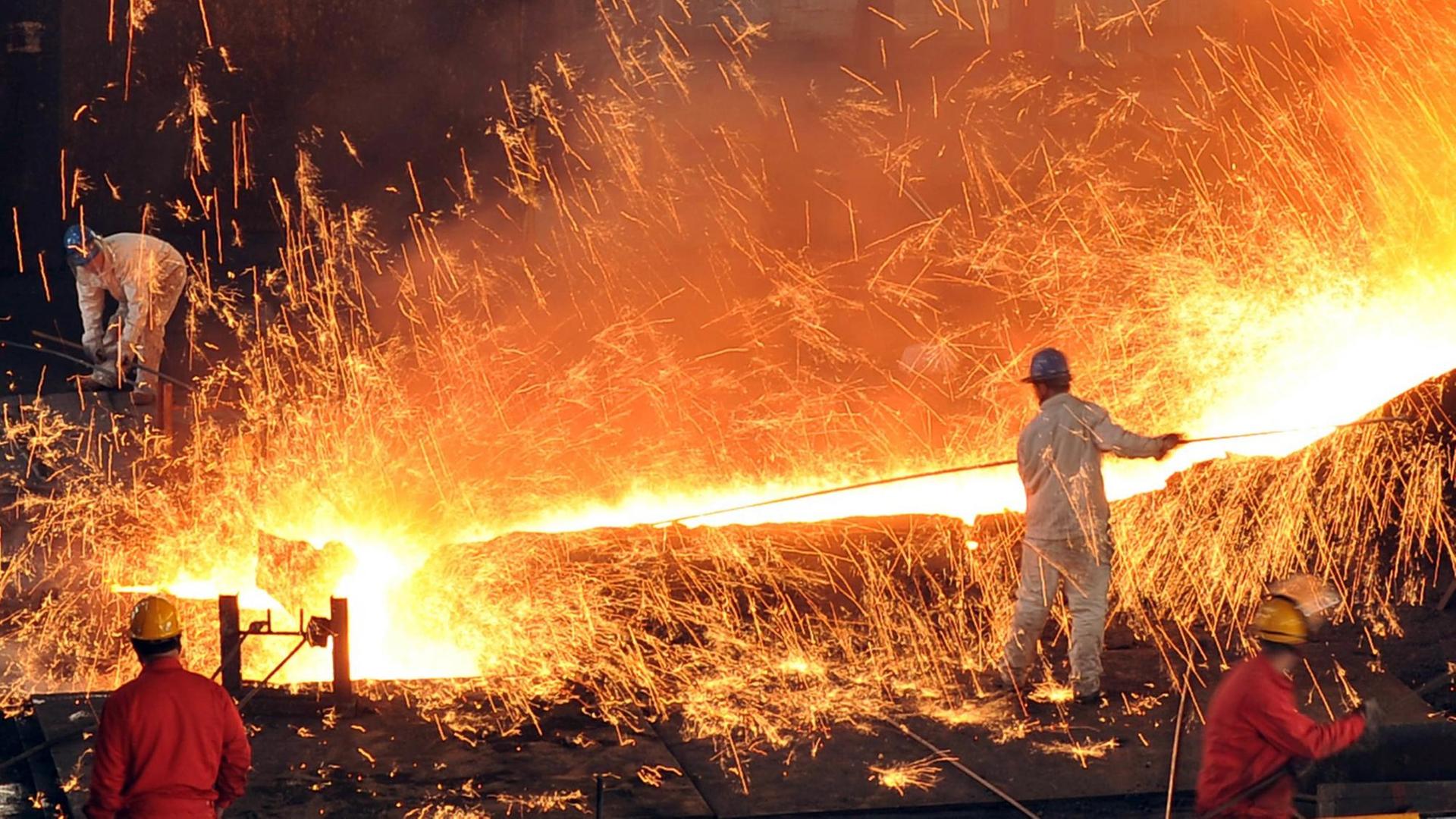 Ein Arbeiter hat einen langen Schieber in der Hand, um flüssigen Stahl zu verarbeiten. Ein Arbeiter hat einen langen Schieber in der Hand, um flüssigen Stahl zu verarbeiten.