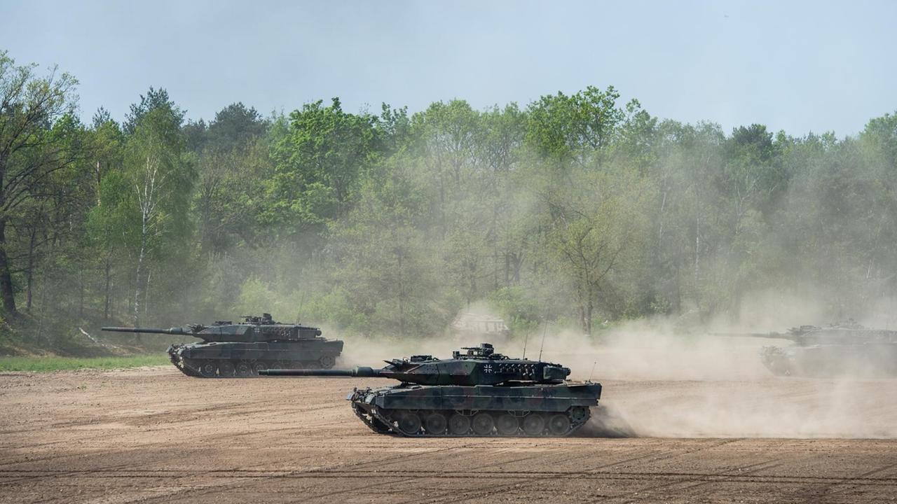 Kampfpanzer vom Typ Leopard 2 fahren auf einem Übungsfeld. Kampfpanzer vom Typ Leopard 2 fahren auf einem Übungsfeld.