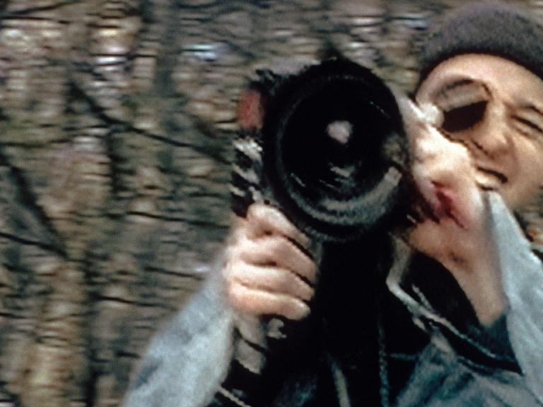 Schauspieler Joshua Leonard blickt auf einem verwackelten Bild mit einer Kamera Richtung Zuschauer.