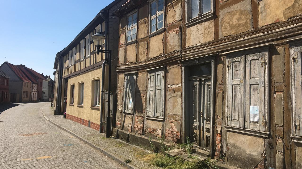 Ein verfallenes Fachwerkhaus steht in einer Straße mit weiteren Fachwerkhäusern in Werben in Sachsen-Anhalt.