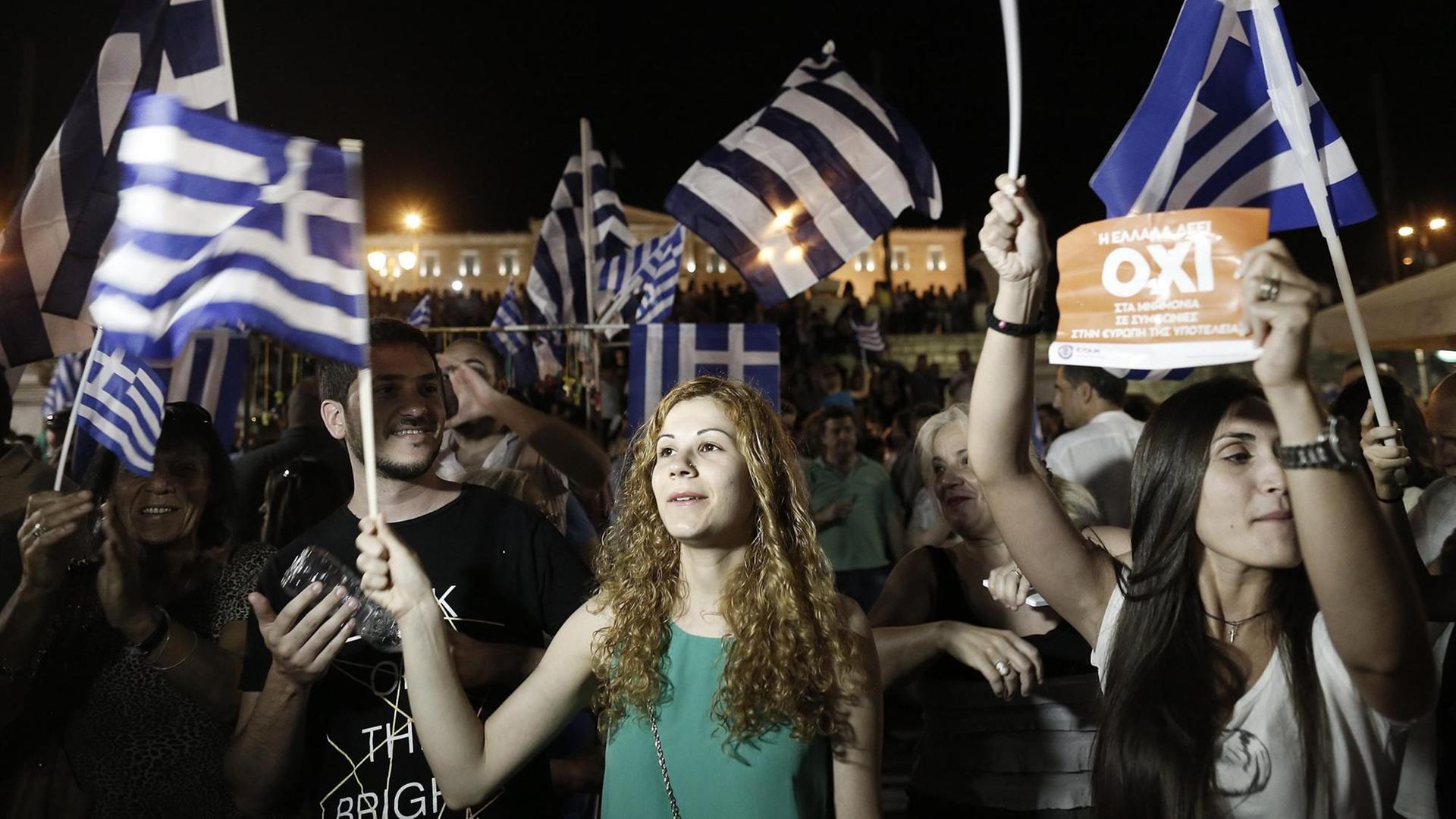 ureJunge Griechinnen feiern in Athen mit Flaggen des Landes in der Hand. ureJunge Griechinnen feiern in Athen mit Flaggen des Landes in der Hand.