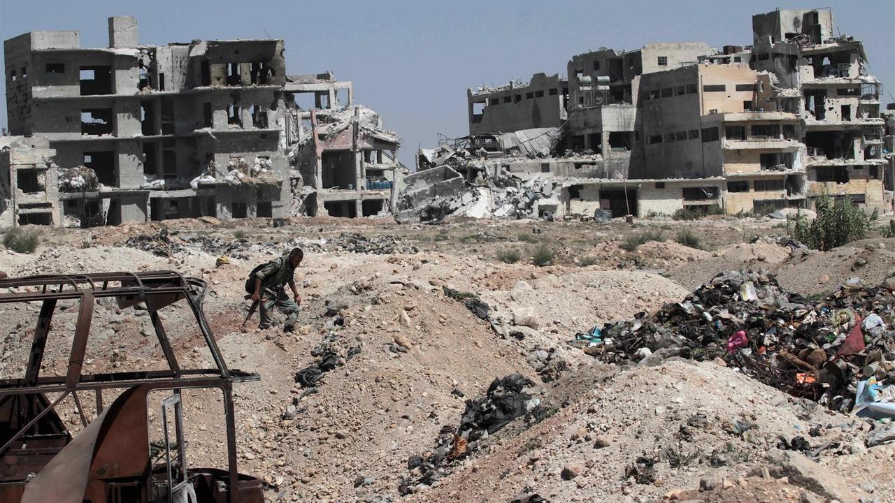 Ein Soldat läuft über Trümmerberge in Aleppo, im Hintergrund stehen die Ruinen mehrerer Häuser Ein Soldat läuft über Trümmerberge in Aleppo, im Hintergrund stehen die Ruinen mehrerer Häuser