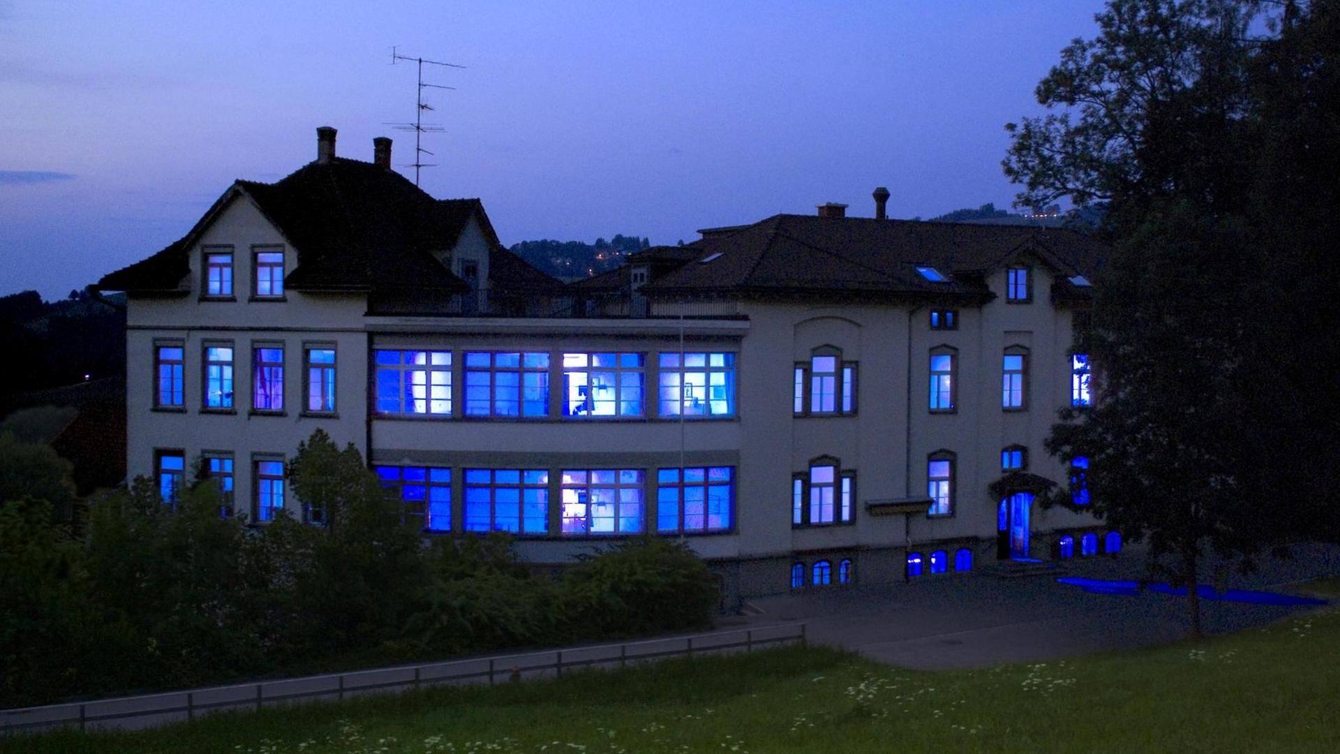 Ein ehemaliges Krankenhausgebäude ist von innen blau erleuchtet Ein ehemaliges Krankenhausgebäude ist von innen blau erleuchtet