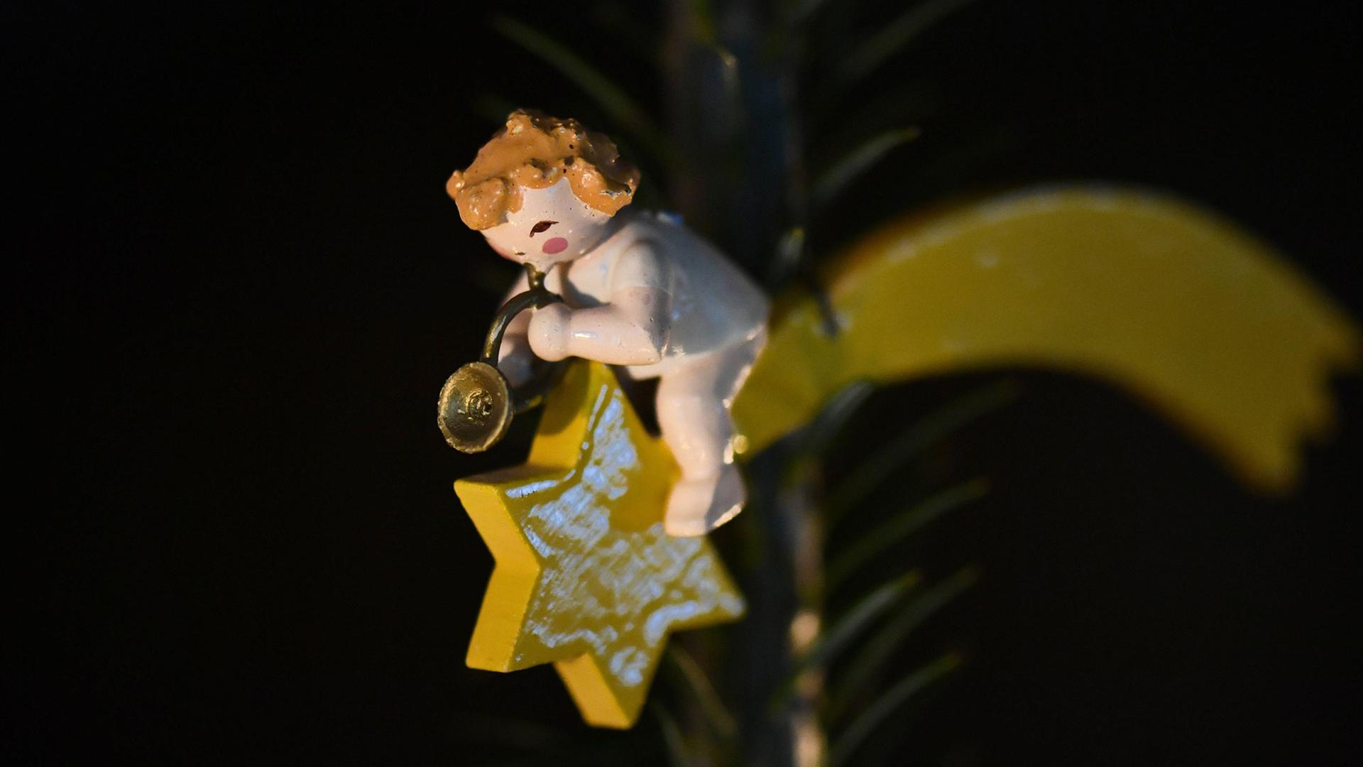 Anhänger an einem Weihnachtsbaum: Ein Holzengel, der in ein Horn bläst, sitzt auf einem Stern mit Schweif. Anhänger an einem Weihnachtsbaum: Ein Holzengel, der in ein Horn bläst, sitzt auf einem Stern mit Schweif.