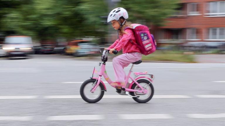 Das Bild zeigt ein kleines Mädchen auf einem Fahrrad im Hamburger Straßenverkehr