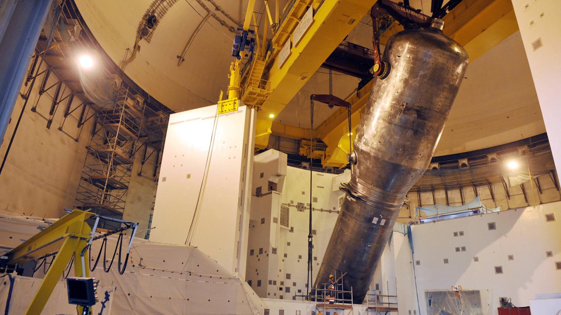 Im Inneren von Olkiluoto 3 wird ein Metallbehälter von einer großen Maschine angehoben. Im Inneren von Olkiluoto 3 wird ein Metallbehälter von einer großen Maschine angehoben.
