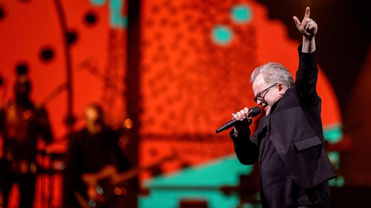 Herbert Grönemeyer steht in einer Rock-Pose auf der rot erleuchteten Bühne Herbert Grönemeyer steht in einer Rock-Pose auf der rot erleuchteten Bühne