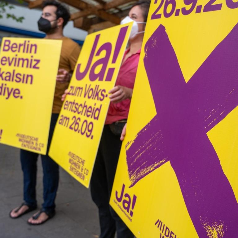 Anhänger der Kampagne "Deutsche Wohnen und Co. enteignen" halten bei einer Veranstaltung Plakate der Kampagne, auf denen für den dazugehörigen Volksentscheid in Berlin geworben wird.