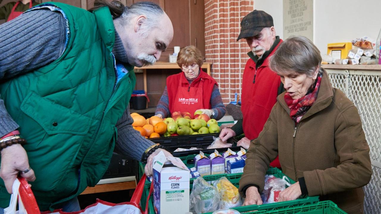 Ehrenamtliche Helfer von "Laib und Seele" sind bei der Essensausgabe von bedürftigen Menschen in einem Vorraum der Evangelischen Advent-Zachäus Kirche beschäftigt. Ehrenamtliche Helfer von "Laib und Seele" sind bei der Essensausgabe von bedürftigen Menschen in einem Vorraum der Evangelischen Advent-Zachäus Kirche beschäftigt.