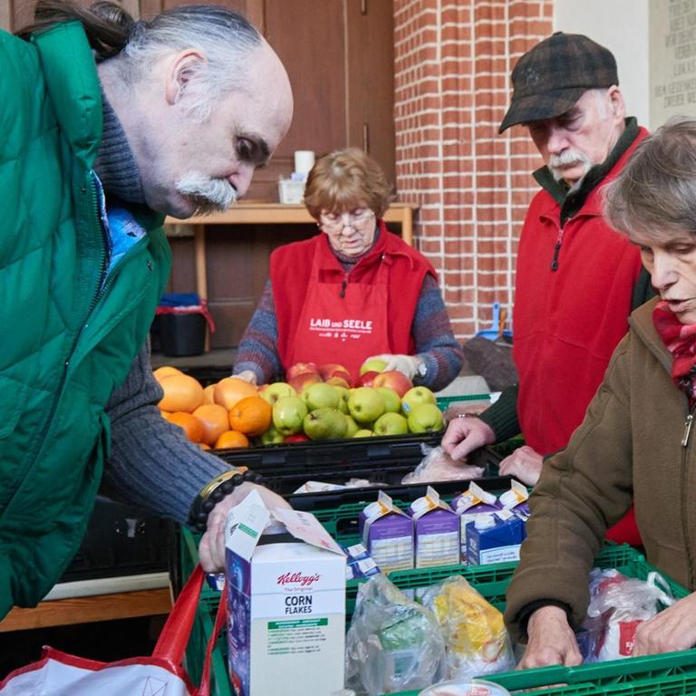 Ehrenamtliche Helfer von "Laib und Seele" sind bei der Essensausgabe von bedürftigen Menschen in einem Vorraum der Evangelischen Advent-Zachäus Kirche beschäftigt.