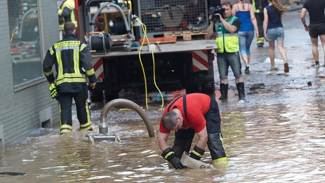Anwohner und Helfer beseitigen am 24.06.2016 in Stromberg (Rheinland-Pfalz) den Schlamm, den ein Unwetter durch Starkregen und Überflutungen verursacht hat.