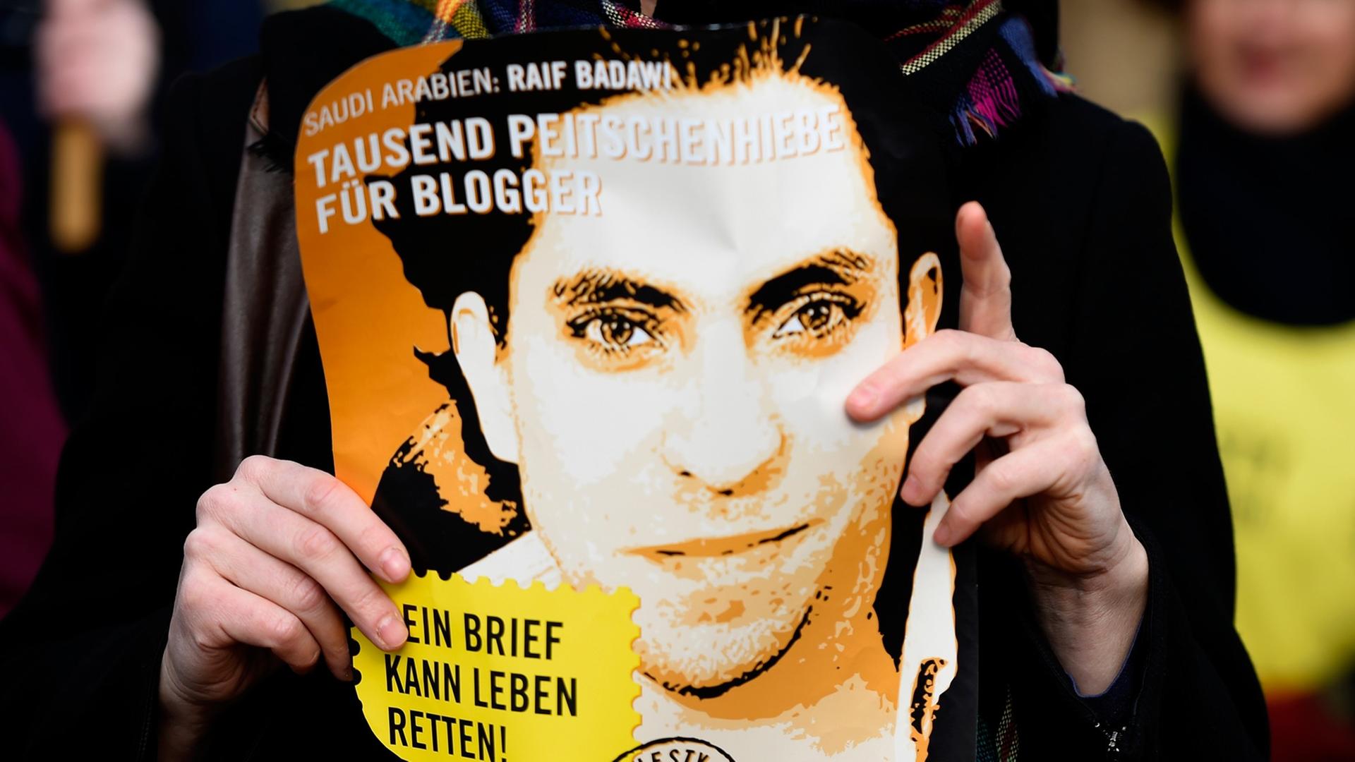Eine Aktivistin von Amnesty International hält ein Plakat mit Raif Badawi hoch und fordert dessen Freilassung bzw. das Ende der Prügelstrafe vor der saudi-arabischen Botschaft in Deutschland am 29. Januar 2015. Eine Aktivistin von Amnesty International hält ein Plakat mit Raif Badawi hoch und fordert dessen Freilassung bzw. das Ende der Prügelstrafe vor der saudi-arabischen Botschaft in Deutschland am 29. Januar 2015.