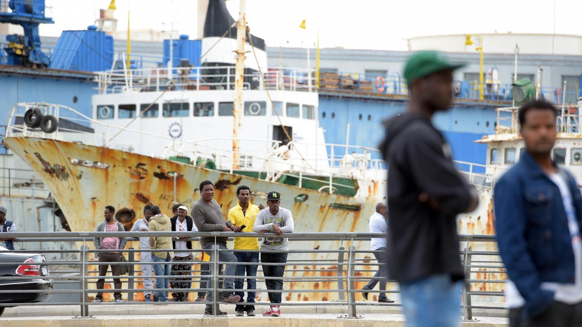 Flüchlinge beobachten am 30.04.2015 am Rande des Geländes eines offenen Flüchtlingszentrum in Marsa (Malta) das Geschehen. Das Flüchtlingszentrum liegt am Rande eines Schiffsfriedhofs. Flüchlinge beobachten am 30.04.2015 am Rande des Geländes eines offenen Flüchtlingszentrum in Marsa (Malta) das Geschehen. Das Flüchtlingszentrum liegt am Rande eines Schiffsfriedhofs.