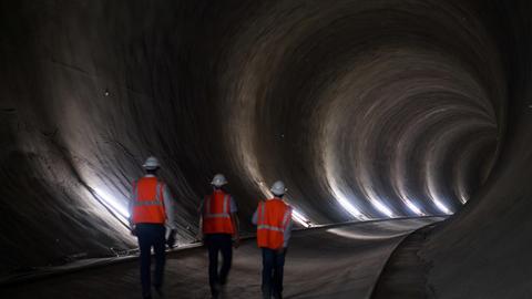 Drei Männer in Warnwesten gehen durch einen Tunnel des Bahnprojektes Stuttgart 21.