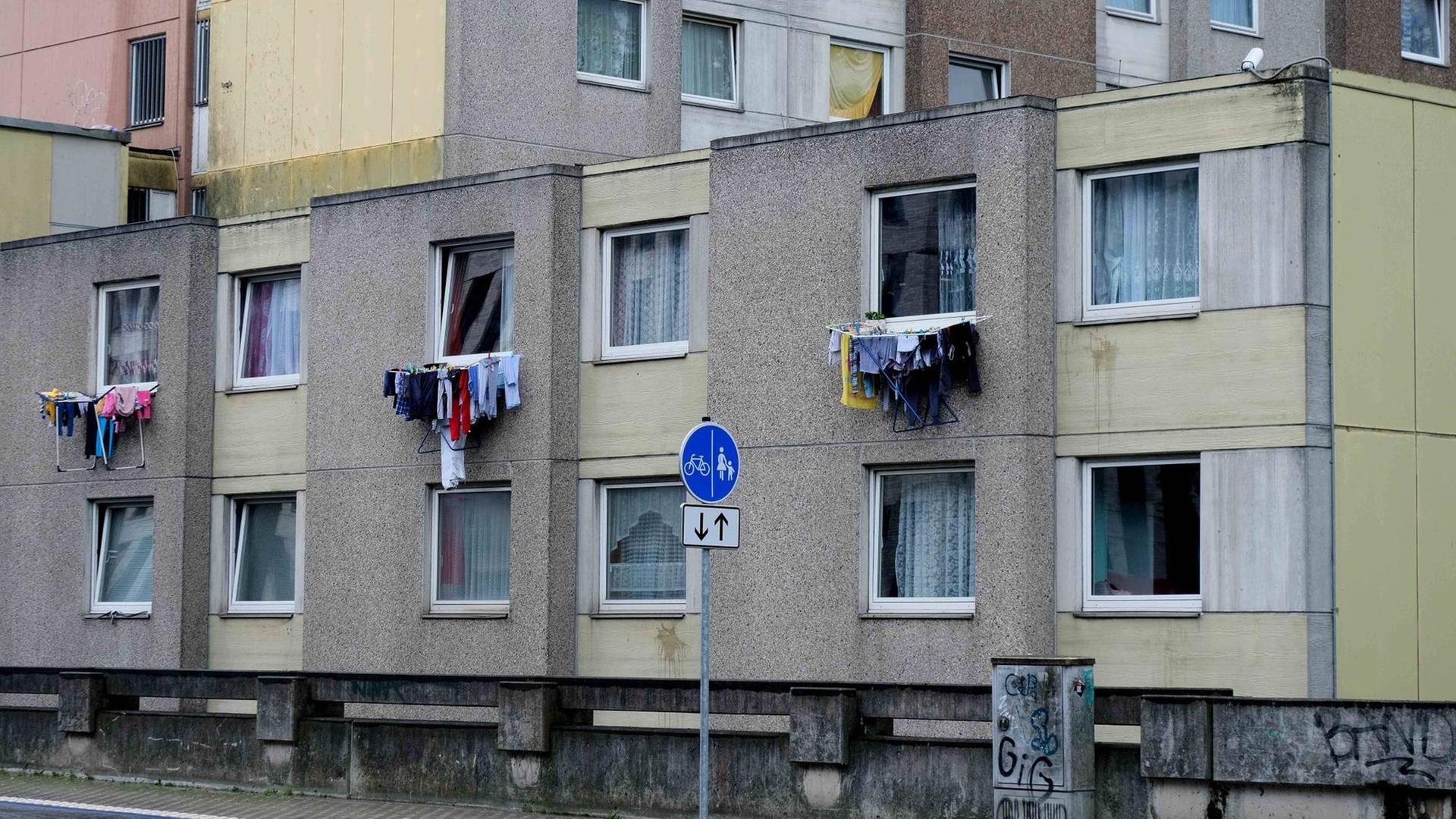 Ein Hochhaus mit einem niedrigeren Anbau, aus drei Fenstern hängt Wäsche Ein Hochhaus mit einem niedrigeren Anbau, aus drei Fenstern hängt Wäsche