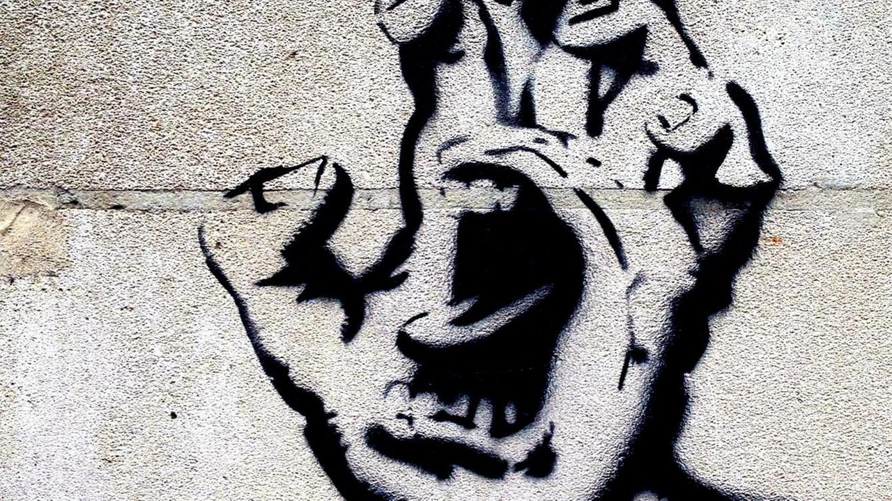 Ein Grafitti zeigt eine Handfläche, in deren Mitte ein Mund aufgerissen schreit.