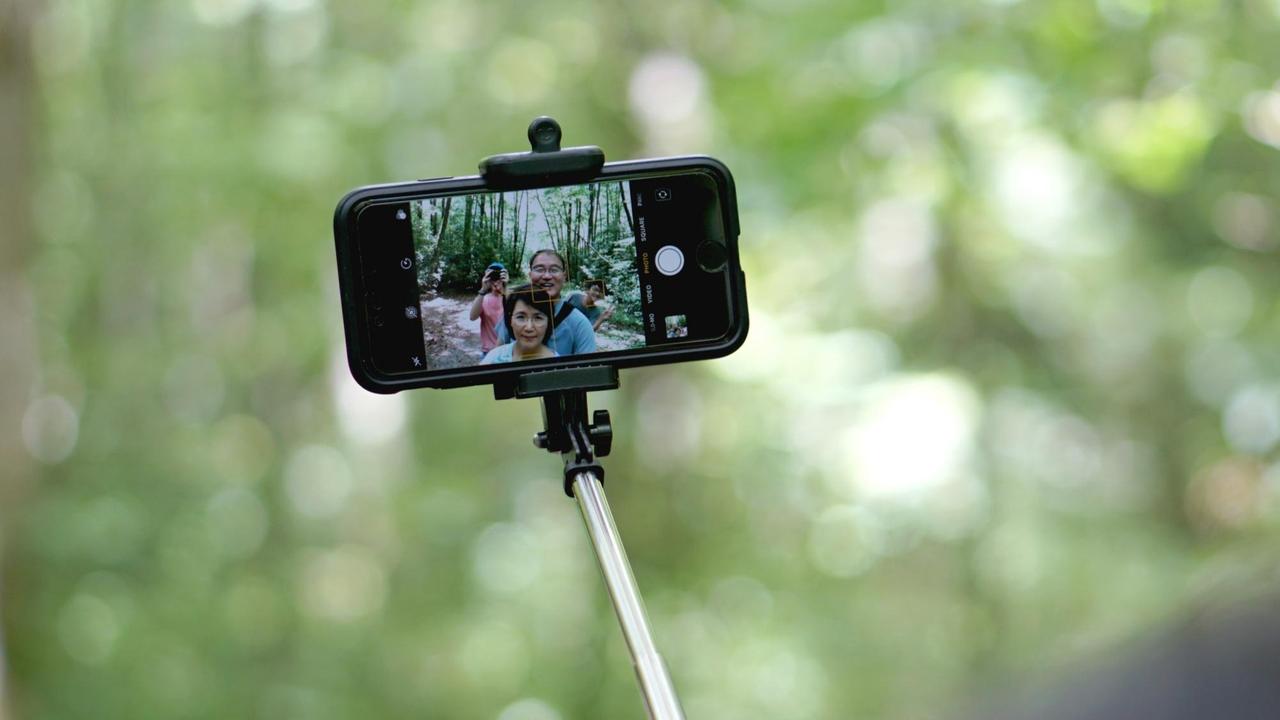 Ein Smartphone an einem Selfie-Stick for grünem Hintergrund in der Natur. Ein Smartphone an einem Selfie-Stick for grünem Hintergrund in der Natur.