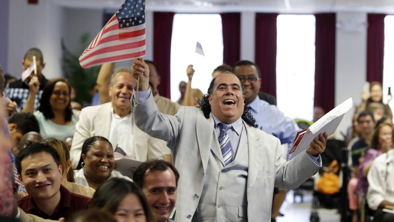 Ein Mann aus der Dominikanischen Republik schwenkt eine US-Flagge und freut sich während der Einbürgerungsveranstaltung im Juli 2013 in New York City. Ein Mann aus der Dominikanischen Republik schwenkt eine US-Flagge und freut sich während der Einbürgerungsveranstaltung im Juli 2013 in New York City.