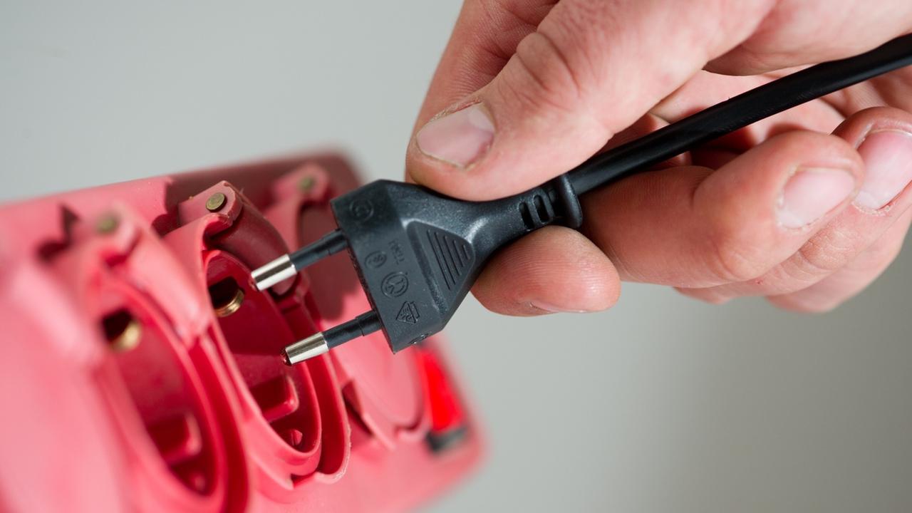 Ein Mann steckt in Berlin einen Stecker in eine Steckerleiste. Ein Mann steckt in Berlin einen Stecker in eine Steckerleiste.