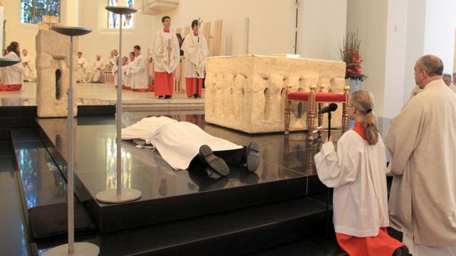 Kilian Krug (l) liegt bei seiner Priesterweihe am Samstag (07.07.2012) flach vor dem Altar im Dom von Rottenburg (Kreis Tübingen). Krug ist ein Symbol für den Priestermangel in der katholischen Kirche geworden. Zum ersten Mal in der Geschichte des Bistums Rottenburg-Stuttgart wurde mit ihm in diesem Jahr nur ein einziger Priester geweiht.