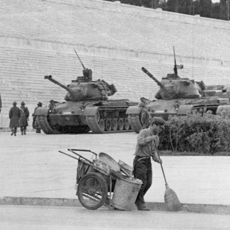 Unbeeindruckt von den Panzern geht im April 1967 ein Straßenkehrer im Stadion von Athen seiner Arbeit nach. 
