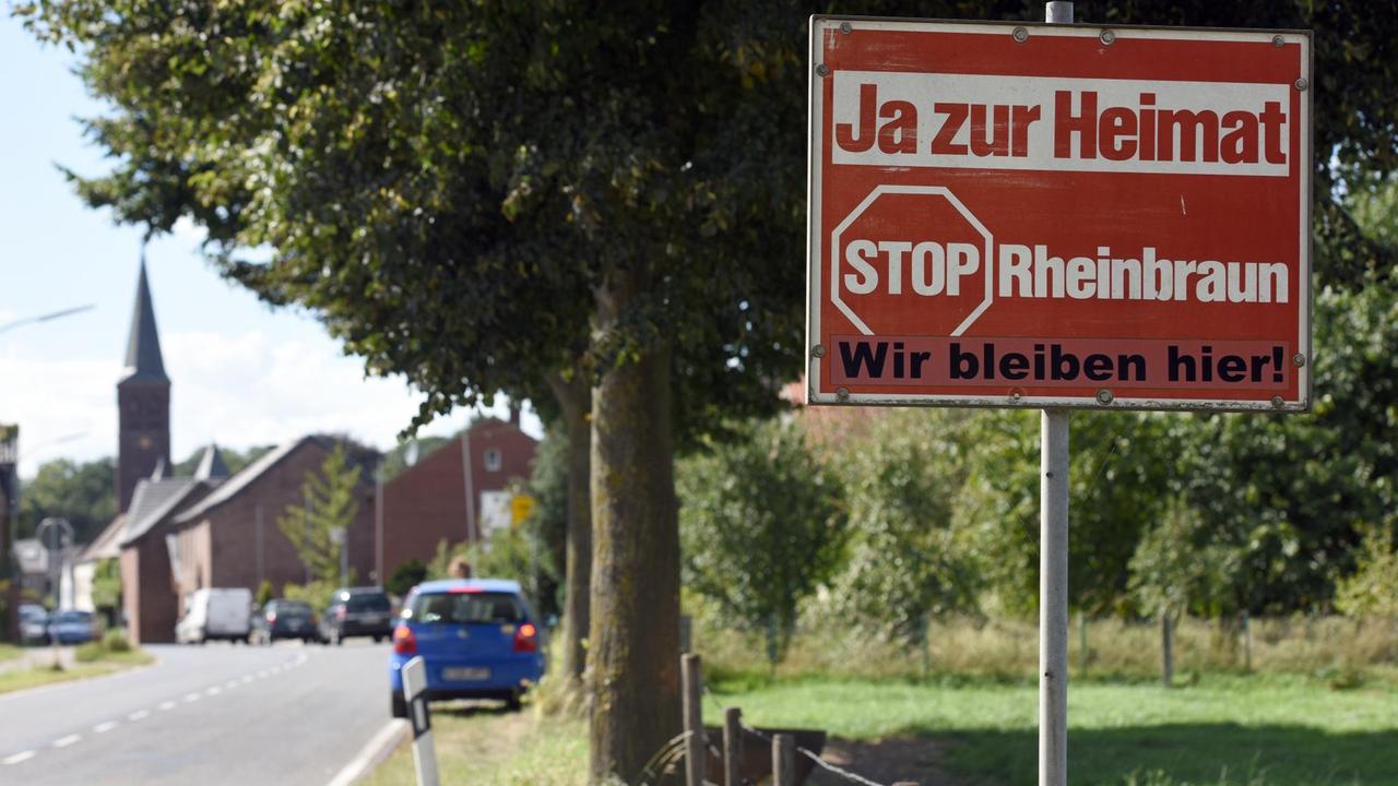 Jahrelang stand dieses Schild am Ortseingang von Keyenberg, bald wird es den Kohlebaggern weichen, so wie die Kirche und Häuser im Hintergrund Jahrelang stand dieses Schild am Ortseingang von Keyenberg, bald wird es den Kohlebaggern weichen, so wie die Kirche und Häuser im Hintergrund