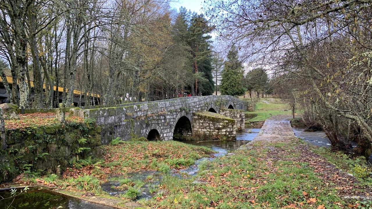 Eine alte Steinbrücke führt über einen Fluß in einer idyllischen Parklandschaft. Eine alte Steinbrücke führt über einen Fluß in einer idyllischen Parklandschaft.