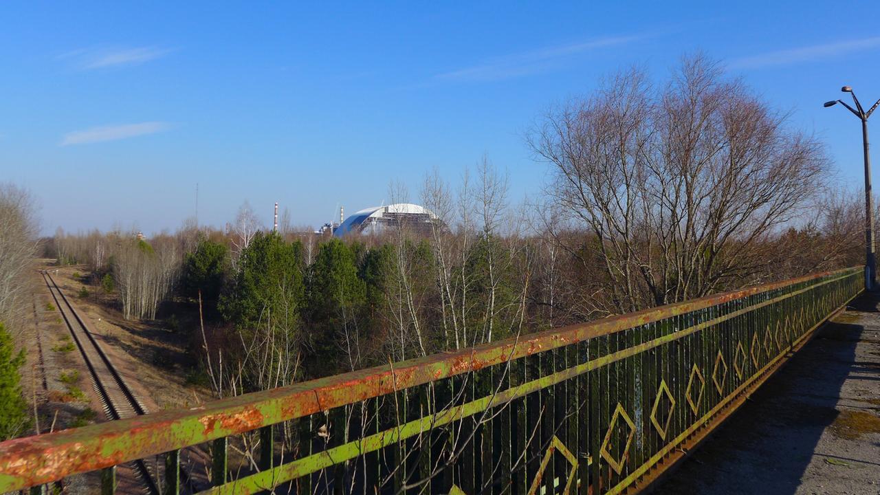 Das New Safe Confinement von der Straße nach Pripjat aus gesehen Das New Safe Confinement von der Straße nach Pripjat aus gesehen
