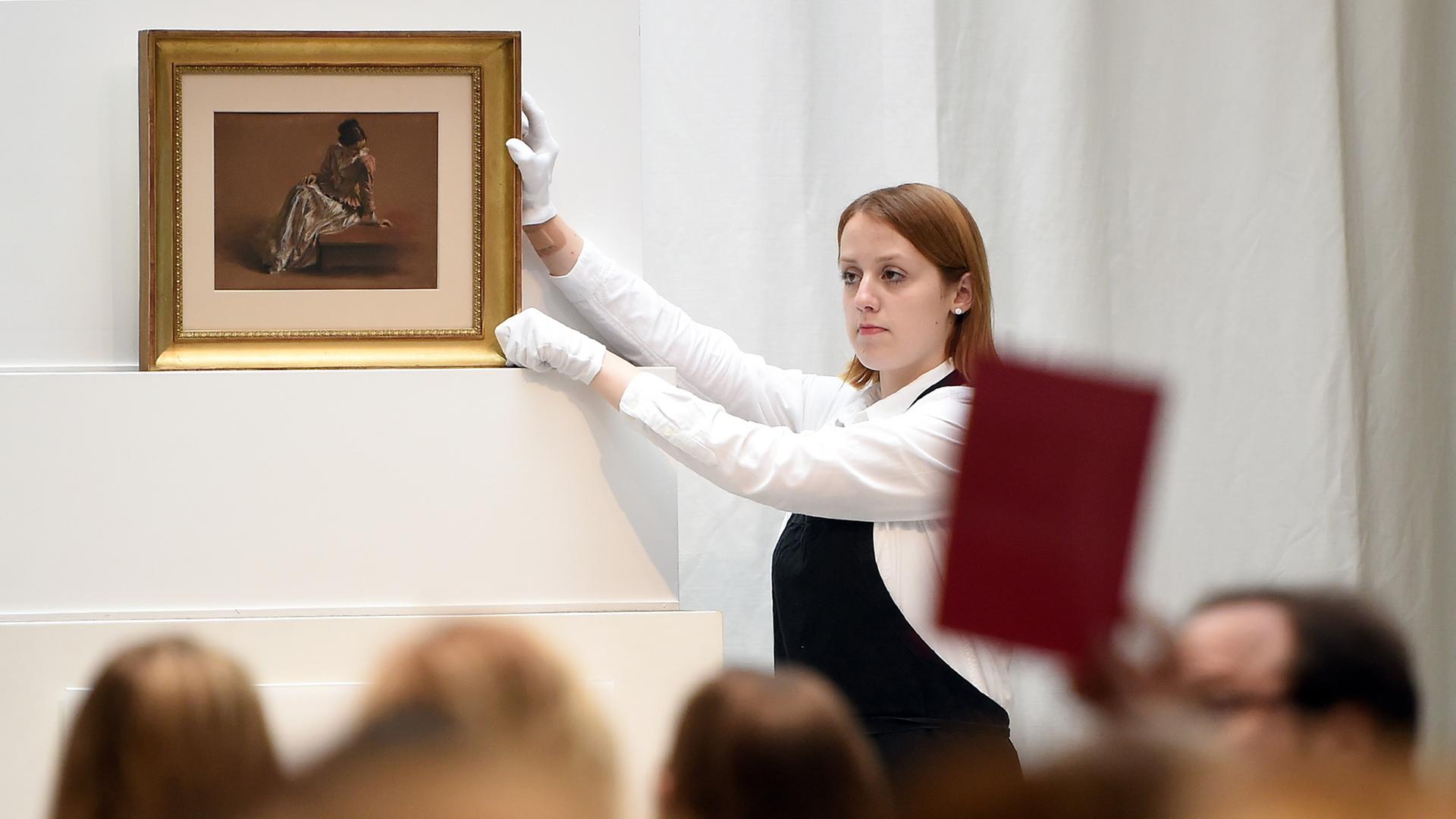 Eine Mitarbeiterin der Villa Grisebach präsentiert in Berlin bei einer Auktion das Werk "Emilie in roter Bluse" von Adolph Menzel. 
