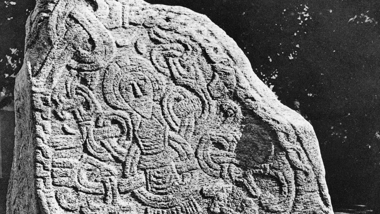 Der Runenstein wurde von Koenig Harald Blauzahn errichtet und zeigt eine Jesus Darstellung mit starken stilistischen Einflüssen der vormaligen Formensprache. (Um 965 n.Chr.) Der Runenstein wurde von Koenig Harald Blauzahn errichtet und zeigt eine Jesus Darstellung mit starken stilistischen Einflüssen der vormaligen Formensprache. (Um 965 n.Chr.)