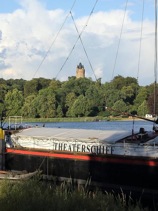 Das Theaterschiff Potsdam am Ufer des Tiefen Sees in der Schiffbauergasse, im Hintergrund der Flatowturm im Park Babelsberg, Potsdam.