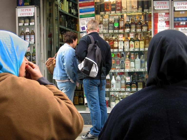 Zwei Musliminnen vor einem Laden mit Tabakwaren und alkoholischen Getränken