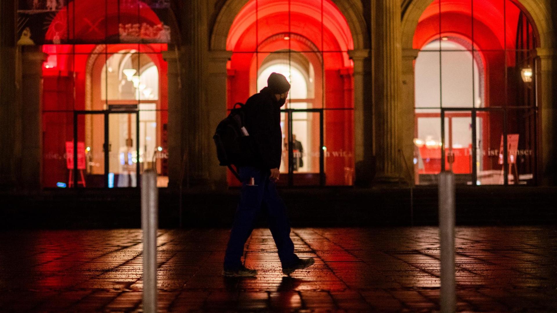 Ein Mann geht am frühen Morgen an der rot illuminierten Oper in Hannover vorbei. Ein Mann geht am frühen Morgen an der rot illuminierten Oper in Hannover vorbei.