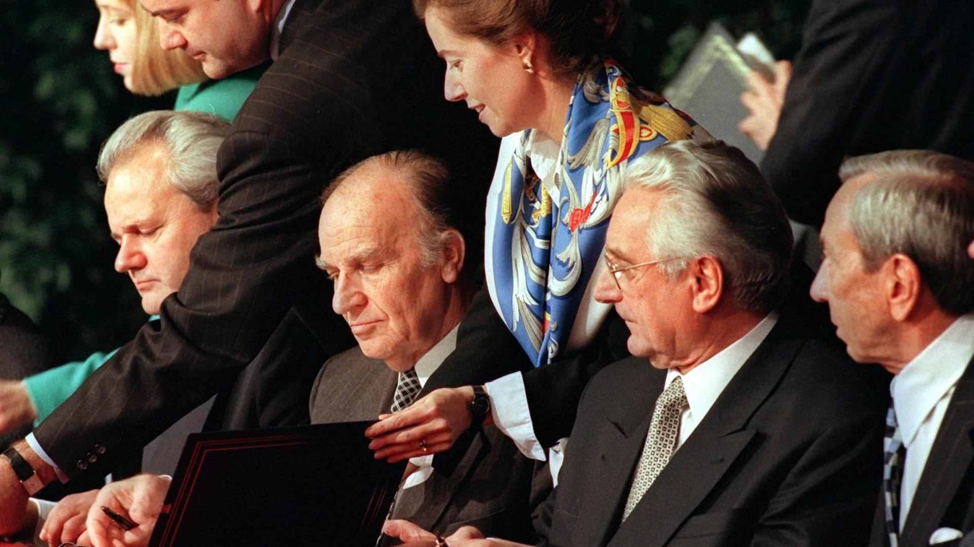 (V.l.) Serbiens Präsident Slobodan Milosevic, sein bosnischer Amtskollege Alija Izetbegovic und der Präsident Kroatiens, Franjo Tudjman, paraphieren am 21. November 1995 auf dem Luftwaffenstützpunkt Wright-Patterson bei Dayton neben US-Außenminister Warren Christopher den Friedensvertrag für Bosnien-Herzegowina.