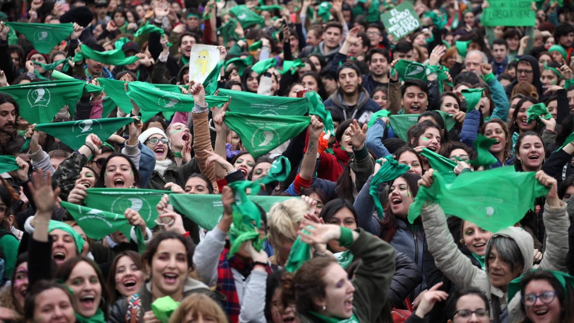 Zum Zeichen ihrer Befüwortung der Legalisierung von Abtreibungen halten viele Menschen grüne Halstücher in die Luft Zum Zeichen ihrer Befüwortung der Legalisierung von Abtreibungen halten viele Menschen grüne Halstücher in die Luft