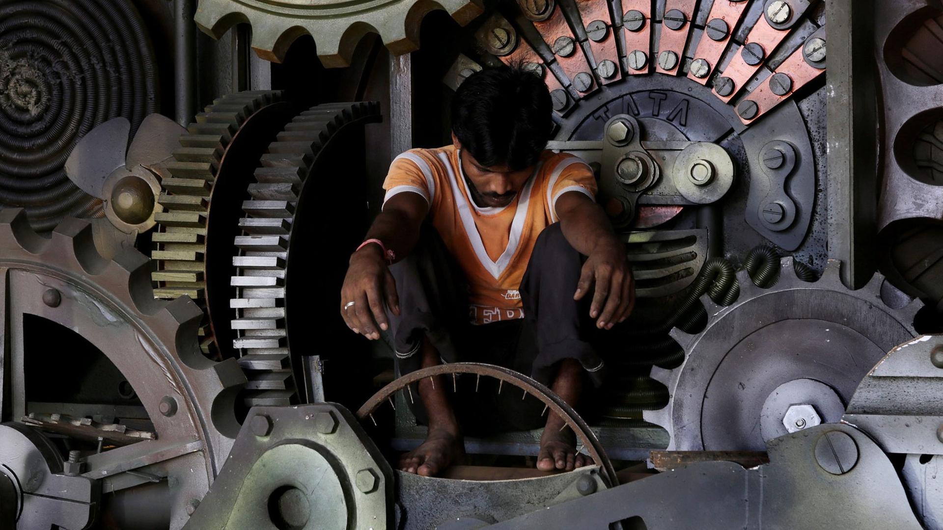Ein indischer Künstler arbeitet im Inneren einer riesigen mechanischen Kuh. Ein indischer Künstler arbeitet im Inneren einer riesigen mechanischen Kuh.