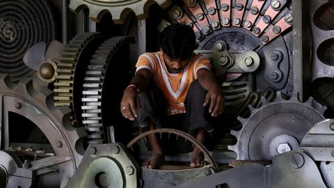 Ein indischer Künstler arbeitet im Inneren einer riesigen mechanischen Kuh.