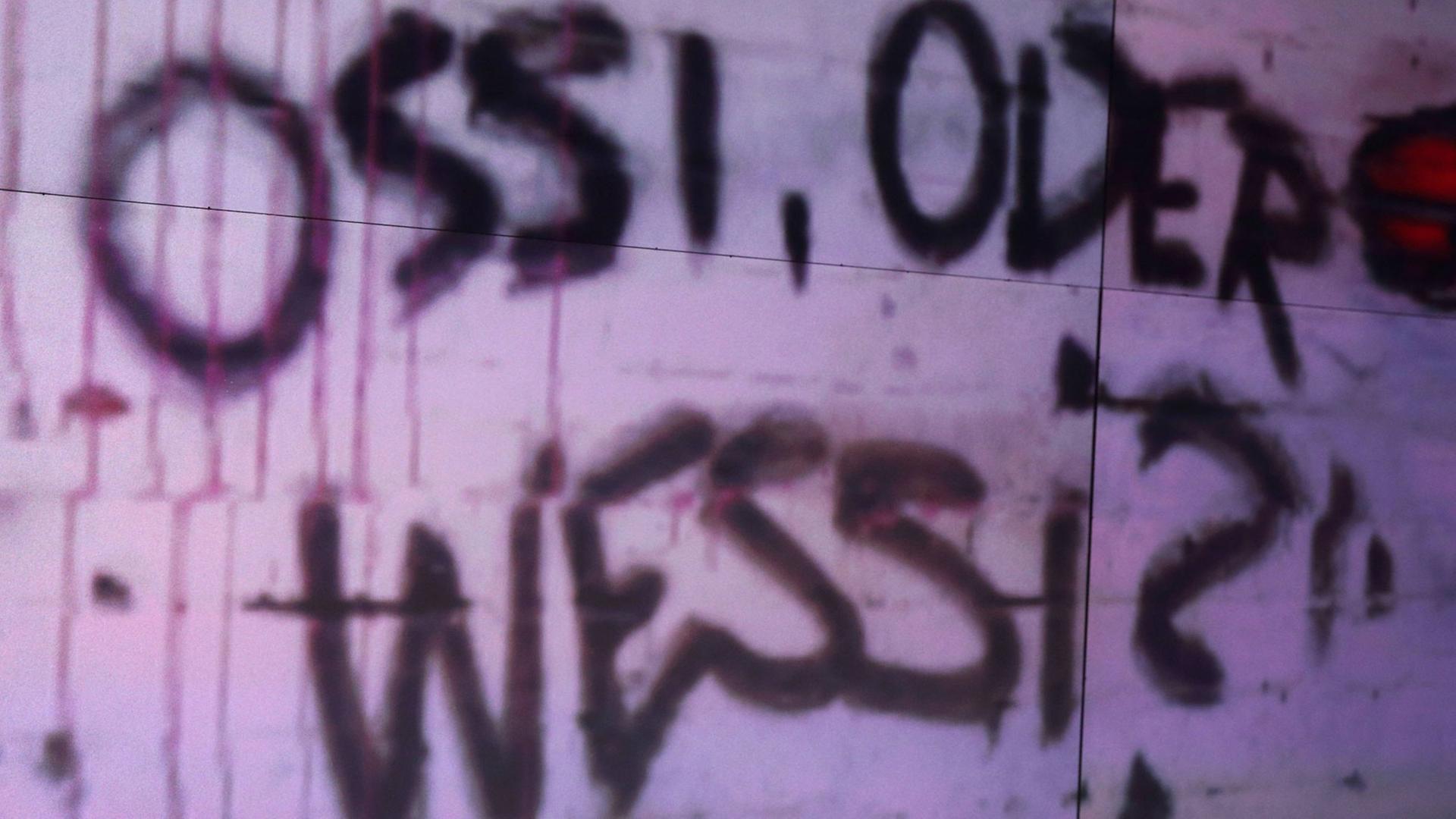 Ossi oder Wessi, fragt ein Graffito an der Wand. Auch 28 Jahre nach der Wiedervereinigung existieren diese Kategorien. Ossi oder Wessi, fragt ein Graffito an der Wand. Auch 28 Jahre nach der Wiedervereinigung existieren diese Kategorien.