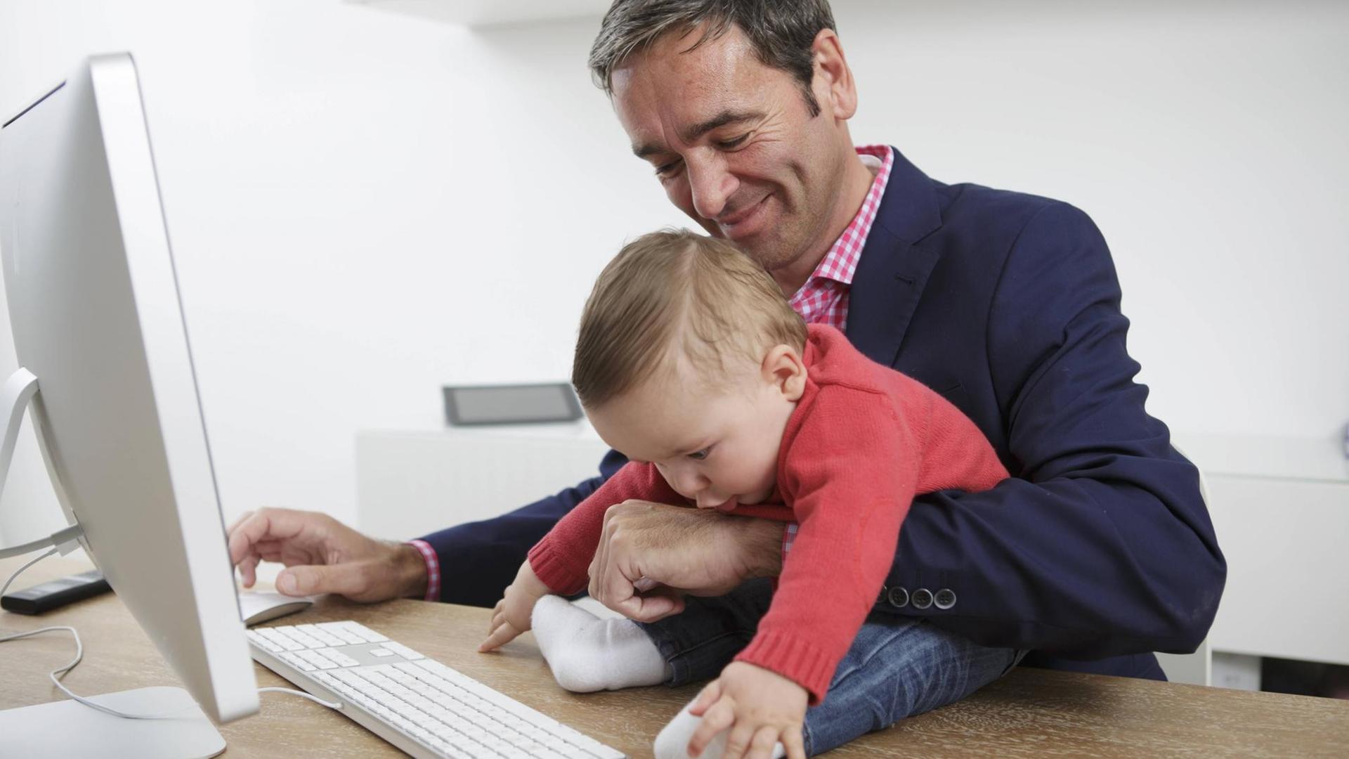 Symbolfoto: Geschäftsmann mit Baby im Arm im Homeoffice Symbolfoto: Geschäftsmann mit Baby im Arm im Homeoffice
