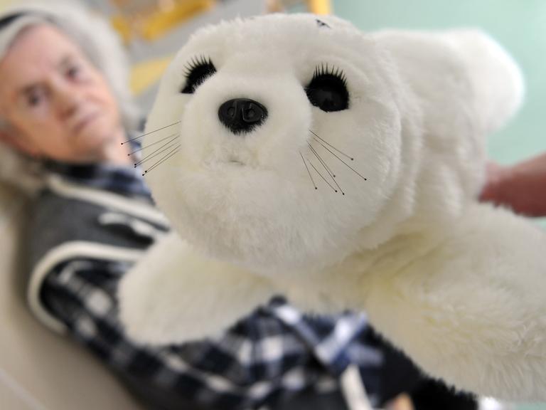 Die demente Eleonore Mayer hält in einem Pflegeheim in Senden einen Roboter in einem Robbenfell.