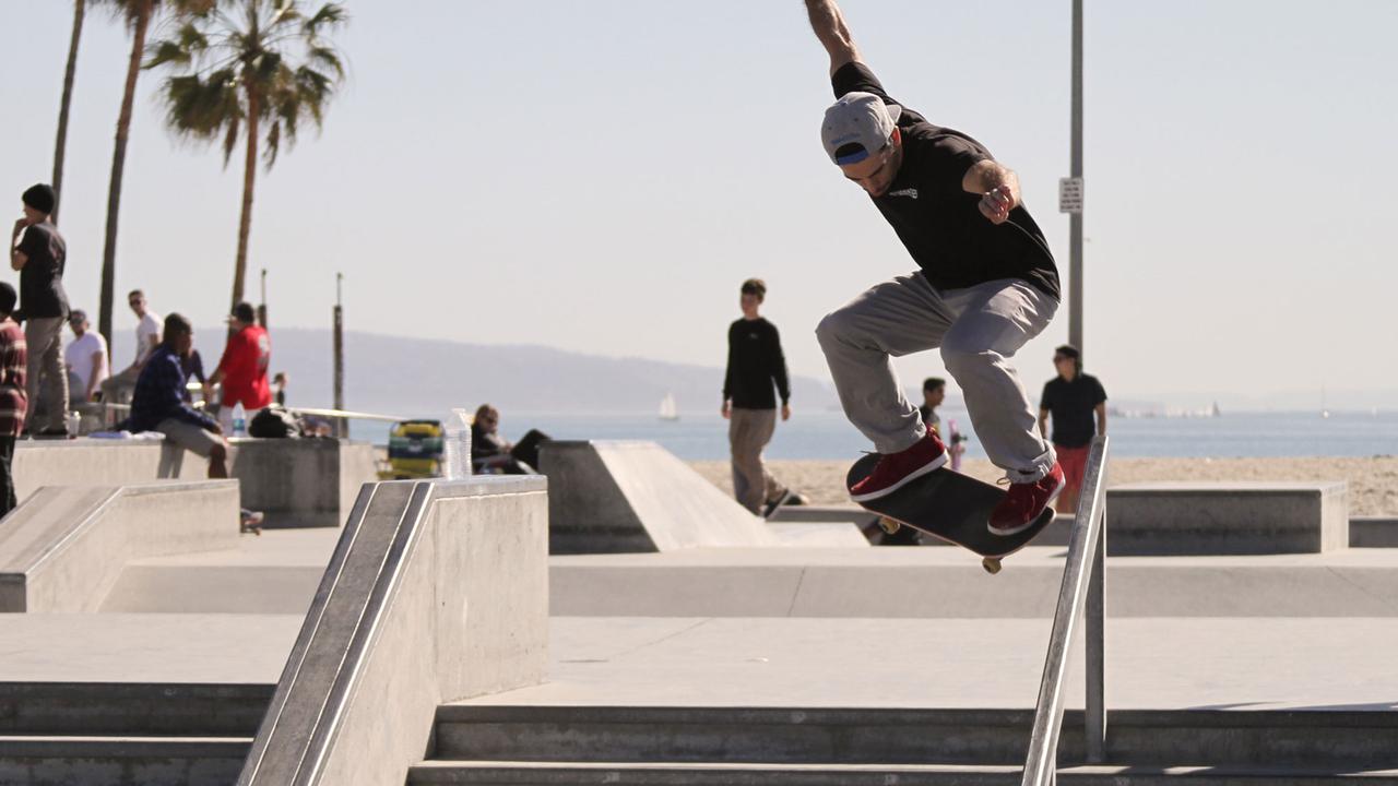 Ein Skater fährt ein Treppengeländer am Strand von Venice, Los Angeles herunter. Ein Skater fährt ein Treppengeländer am Strand von Venice, Los Angeles herunter.