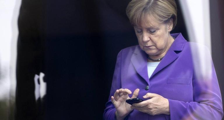 Angela Merkel schaut auf ihr Handy. Angela Merkel schaut auf ihr Handy.
