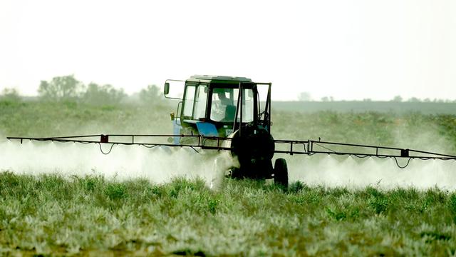 En Traktor versprüht Pestizide auf einem Feld.