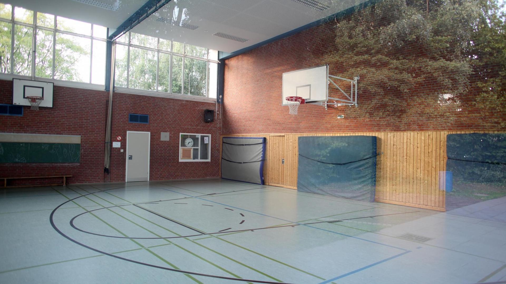 Der Blick durch eine Fensterscheibe zeigt eine leere Turnhalle. Der Blick durch eine Fensterscheibe zeigt eine leere Turnhalle.