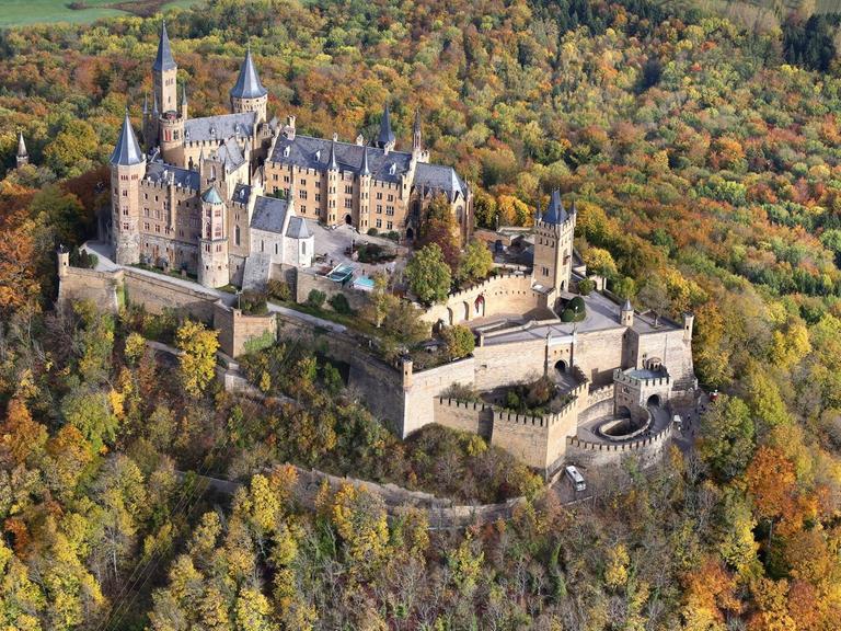 Die Burg Hohenzollern bei Bisingen umrahmt von herbstlich gefärbten Bäumen.