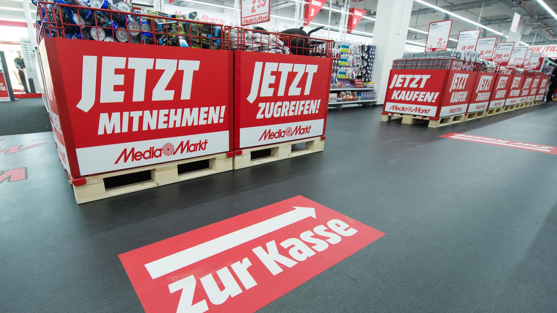 Schilder mit der Aufschrift "Jetzt Mitnehmen!" und "Zur Kasse" sind in einem Media Markt in Ingolstadt (Bayern) angebracht.