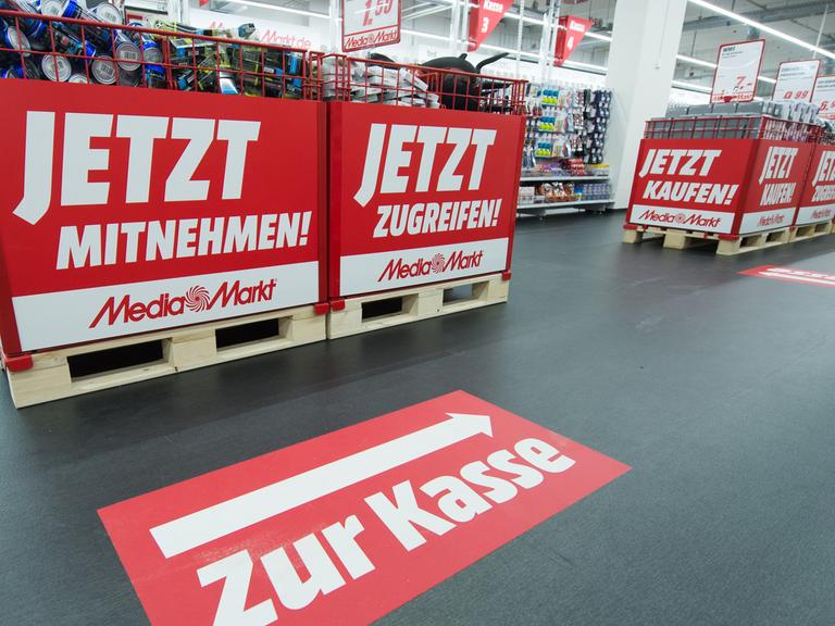 Schilder mit der Aufschrift "Jetzt Mitnehmen!" und "Zur Kasse" sind in einem Media Markt in Ingolstadt (Bayern) angebracht.