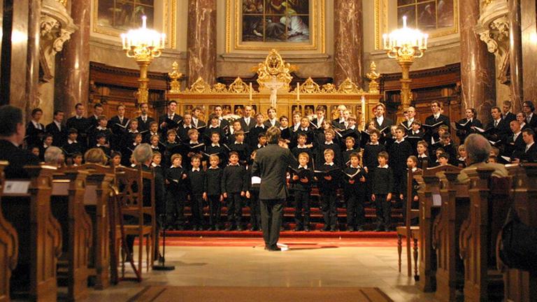 Der Chor steht in einem hell illuminierten Kirchenraum. Der Chor steht in einem hell illuminierten Kirchenraum.
