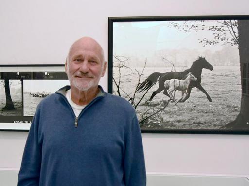 Porträt des Fotografen Peter Thomann vor seinem berühmten schwarz/weiss Foto "Stute mit Fohlen".