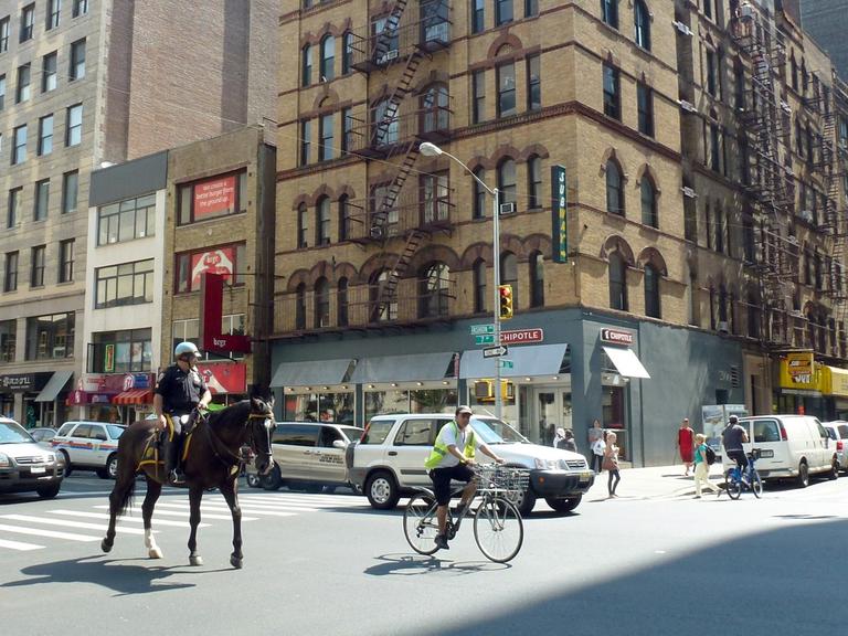 Ein berittener Polizist überquert am 17.08.2013 die Kreuzung Seventh Avenue und 26th Street in Chelsea, New York City.